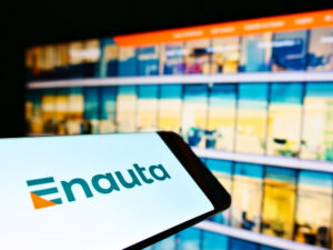 Telefone celular com logotipo da Enauta e monitor com imagens ao fundo