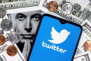celular com logo do twitter cercado por uma foto de Elon Musk e de dólares americanos
