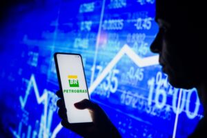 Pessoa com logo da petrobras e gráfico de ações no fundo