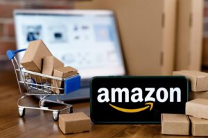 mini-carrinho de supermercado com caixas ao lado de celular com o logotipo da Amazon exibido na tela