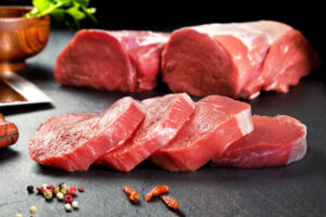 Medalhões de carne em cima de uma base preta, com temperos à frente e ao fundo.